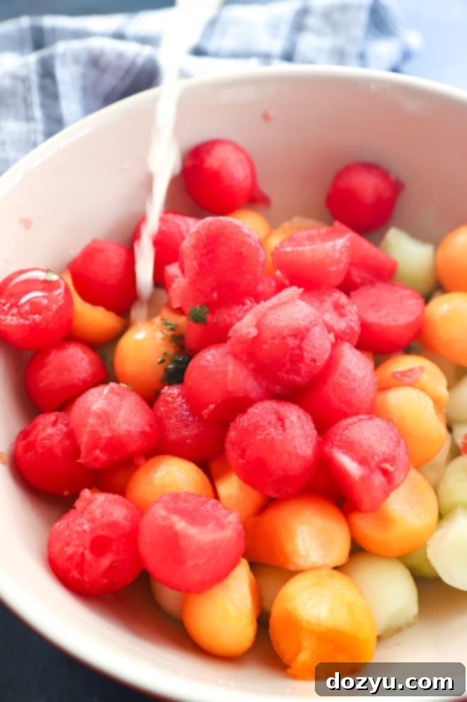 Sweet and Salty Melon Prosciutto Salad 9 Pouring on dressing onto fruit in bowl