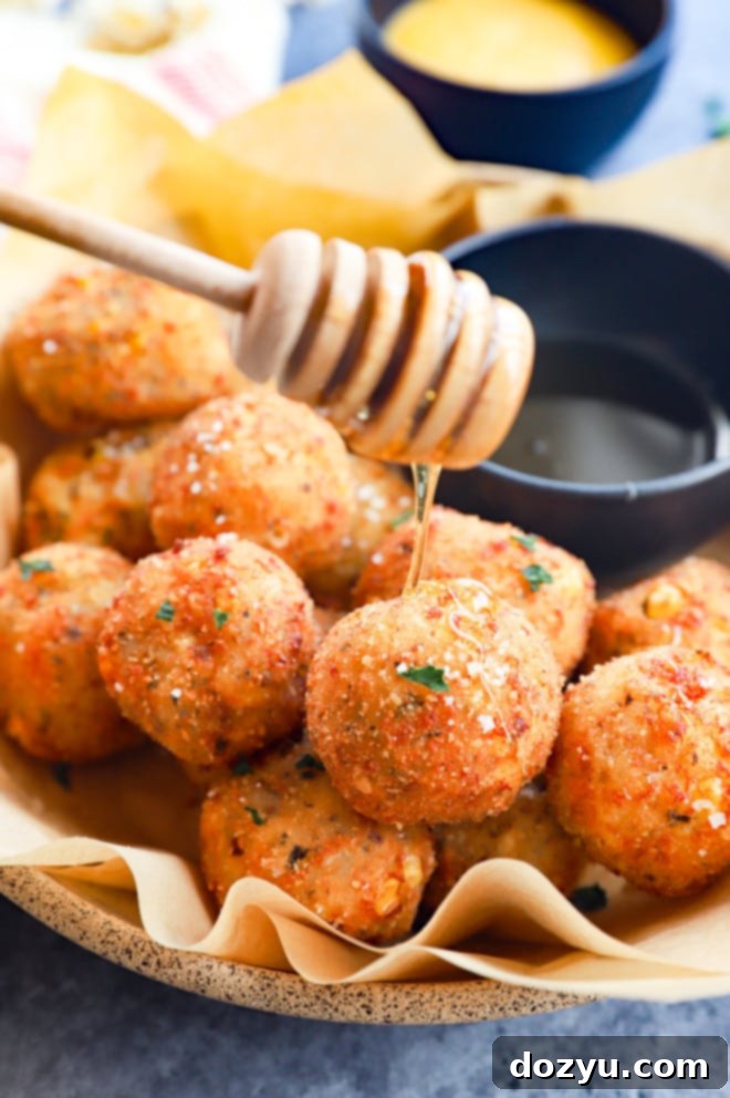 Cheesy Corn Bites 10 Hand drizzling honey over a bowl of freshly fried cheese corn balls, creating a sweet and savory glaze.