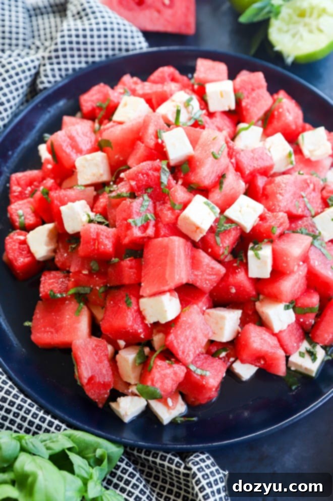 Refreshing Watermelon Feta Delight 5 Close-up of cubed watermelon mixed with chunks of feta cheese and green basil leaves in a bowl, highlighting the fresh ingredients and vibrant colors of the salad.