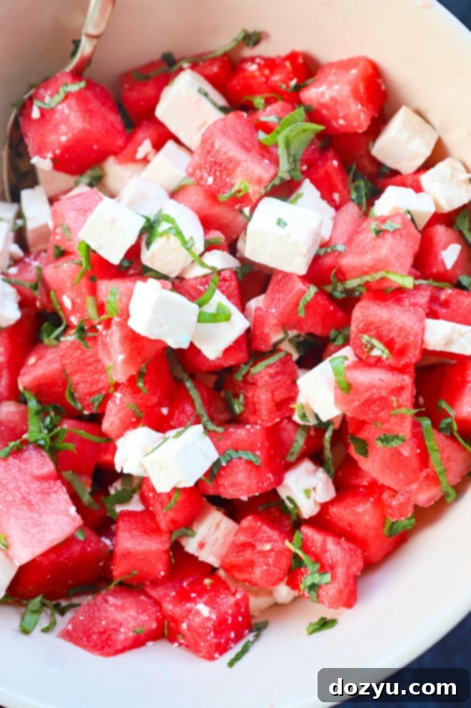 Refreshing Watermelon Feta Delight 6 A vibrant summer salad in a stylish bowl, filled with red watermelon cubes, white feta cheese, and green fresh herbs, perfectly dressed and ready to be served.