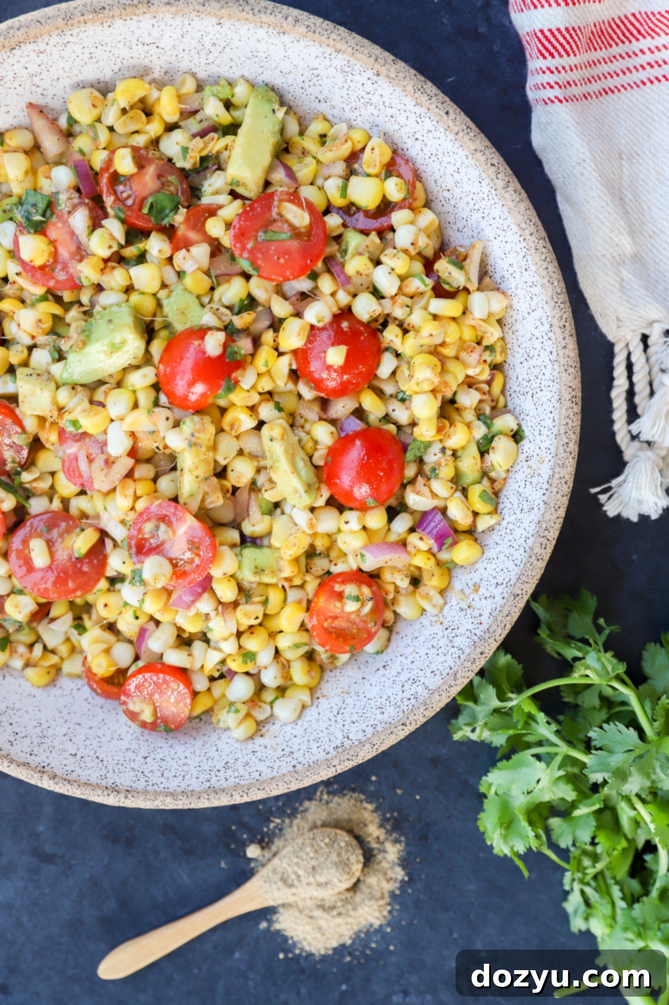 Vibrant Masala Corn Salad 7 Overhead view of a beautifully arranged Masala Corn Salad, featuring corn, halved tomatoes, diced avocado, and a sprinkle of chaat masala.