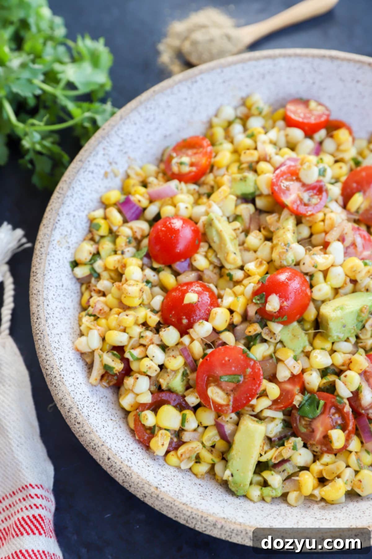 Vibrant Masala Corn Salad 9 Masala corn salad in a bowl with fresh tomatoes and avocado, garnished with cilantro.