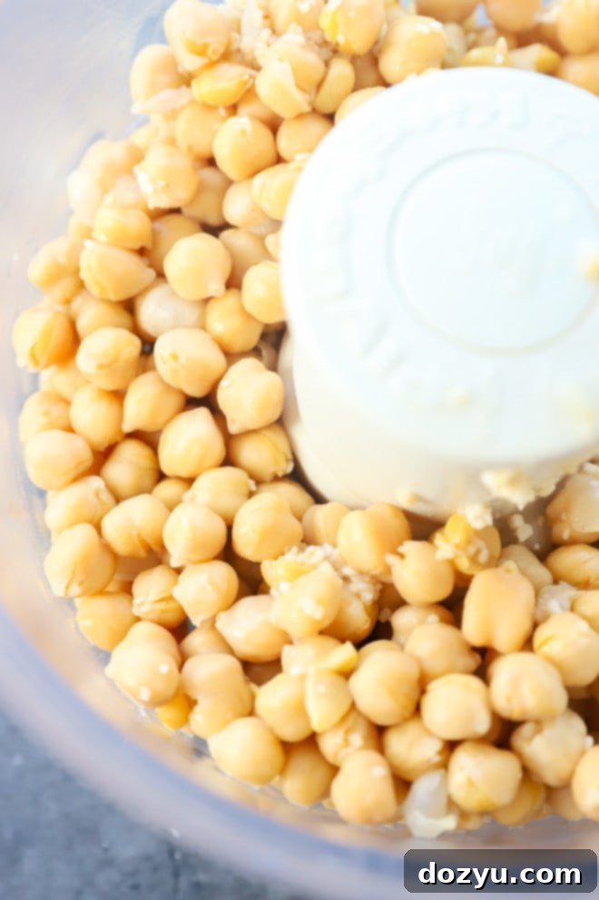 Chickpeas and garlic being pureed in a food processor for homemade hummus
