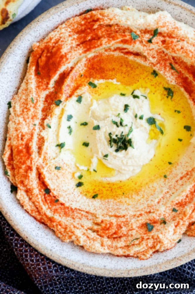 Homemade Greek style hummus in a bowl, drizzled with olive oil and garnished.
