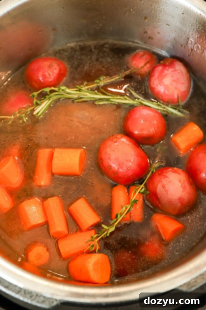 Fork-Tender Instant Pot Pot Roast 7 potatoes and carrots on top of seared chuck roast in electric pressure cooker