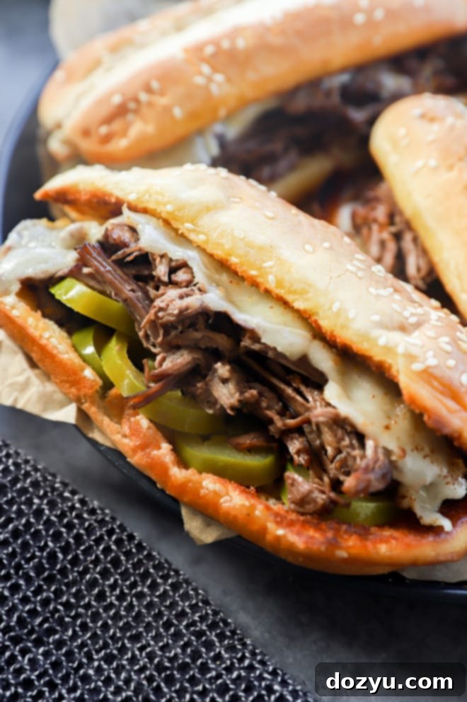 Ultimate French Dip 2 Image of a beef sandwich with hot peppers and cheese, ready to be dipped