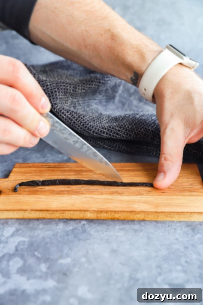 Craft Your Own Vanilla Extract 5 A sharp knife carefully slicing a vanilla bean open on a wooden cutting board to expose the seeds