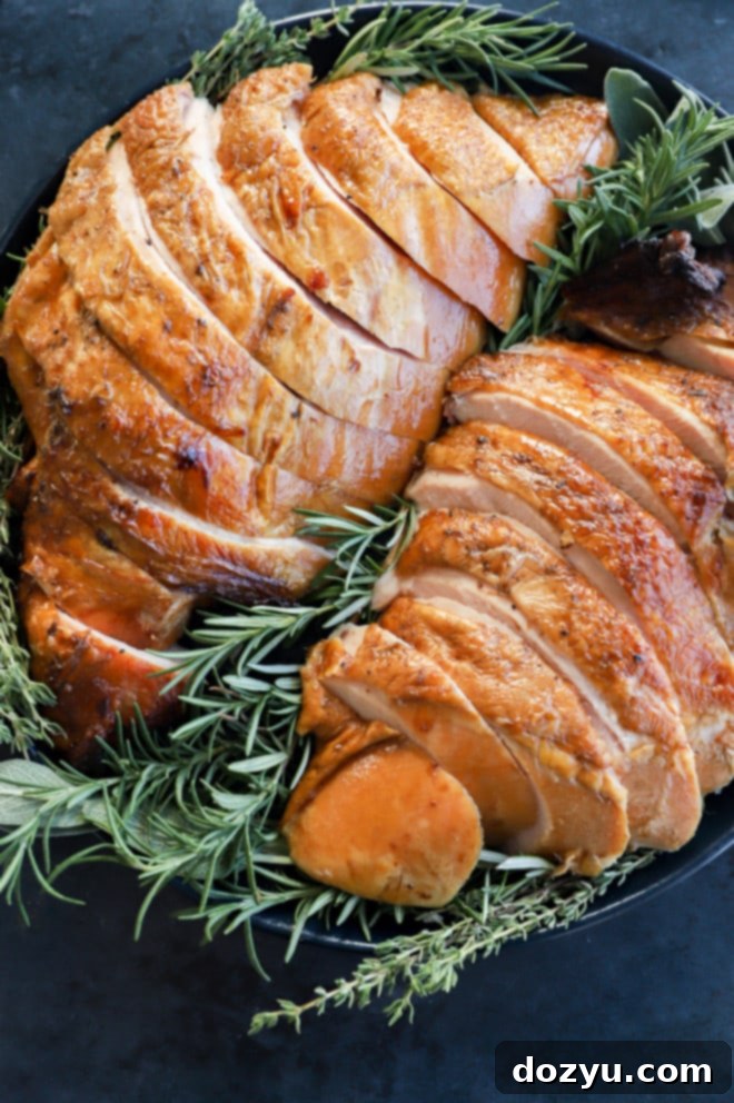 Ultimate Turkey Brine 2 sliced thanksgiving smoked turkey breast on a plate with herbs