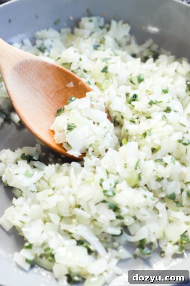 Perfect Sage and Onion Stuffing 6 A large skillet containing sautéed onions, celery, garlic, and herbs, creating the aromatic base for the stuffing.