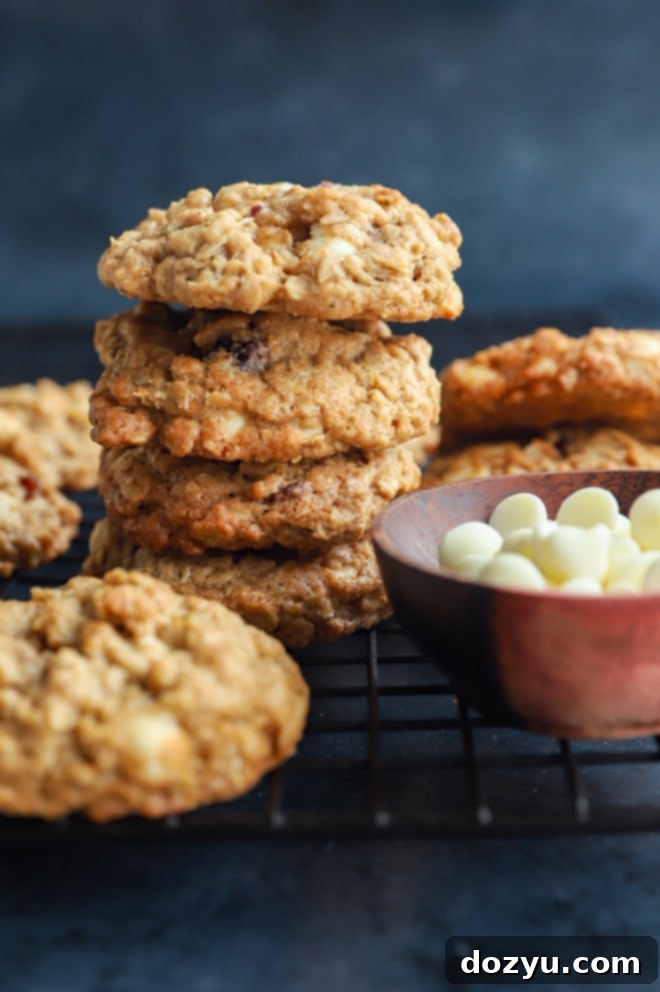 Cranberry White Chocolate Oatmeal Delights 9 stack of cookies on a wire rack with white chocolate chips