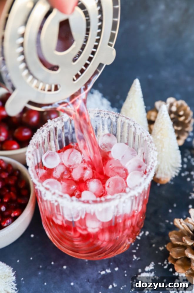 Frosted Fiesta Margarita 5 Pouring a cranberry pomegranate cocktail into a glass with ice