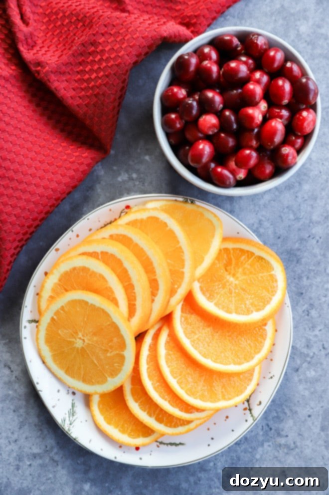 Your Guide to Festive Christmas Punches 3 orange slices on a plate and fresh cranberries in a bowl