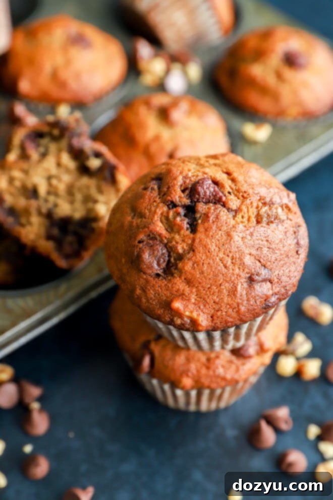 Golden Banana Muffins 8 A stack of banana bread muffins, garnished with fresh bananas, chocolate chips, and walnuts.