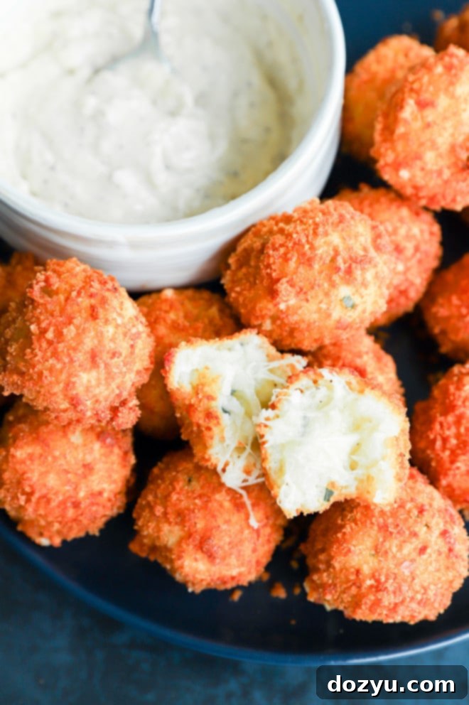 Golden Cheesy Potato Bites 9 Potato cheese ball torn in half to show the gooey cheese inside, highlighting the desirable cheese pull