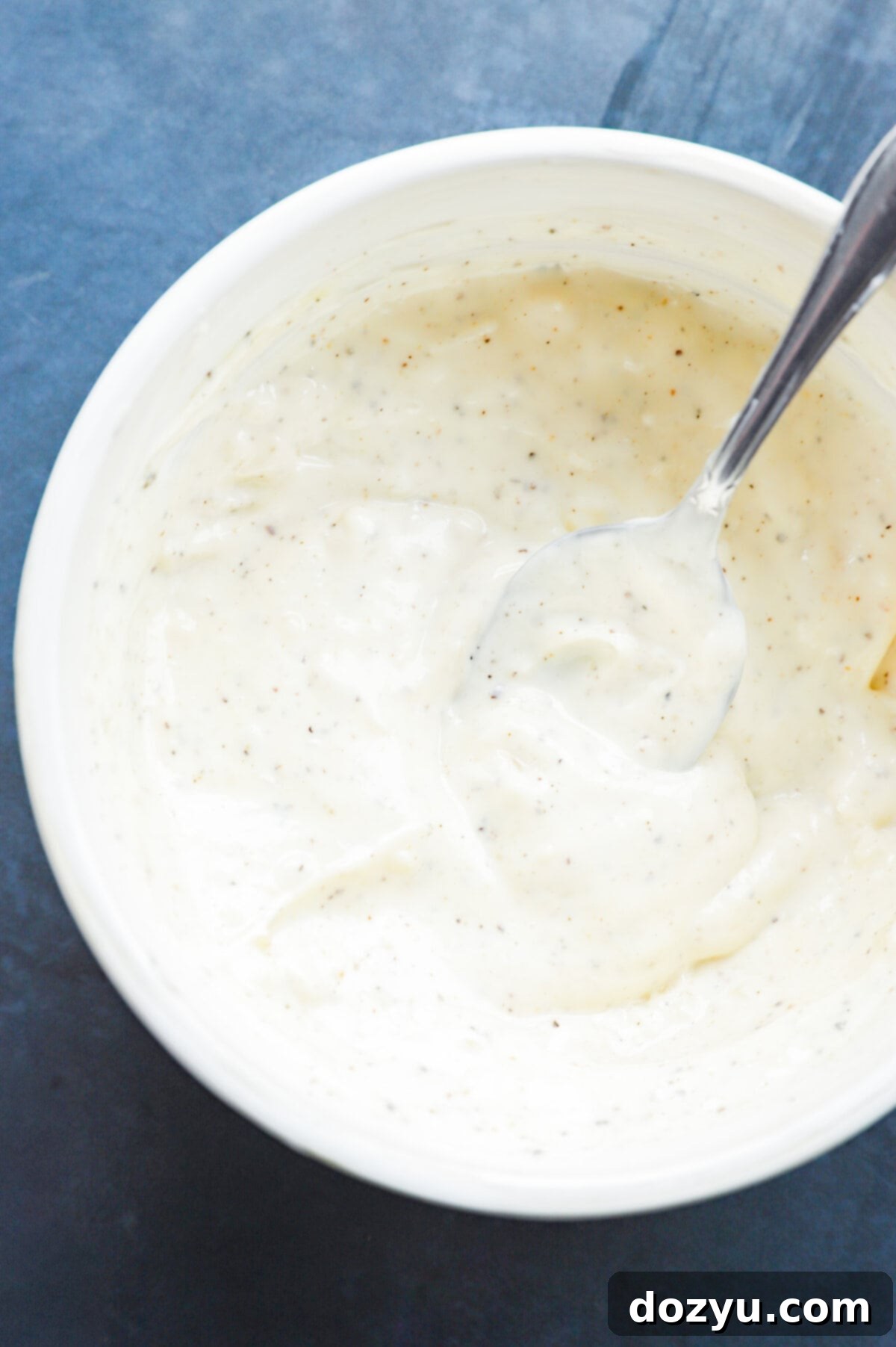 Creamy garlic aioli in a bowl with a spoon
