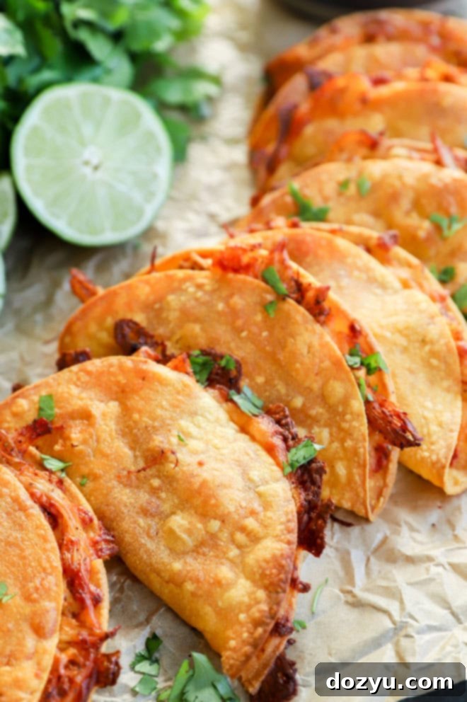 Zesty Crispy Chicken Tacos with Creamy Avocado Tomatillo 5 A sheet pan filled with golden-brown crispy baked chicken tacos, arranged neatly after baking.