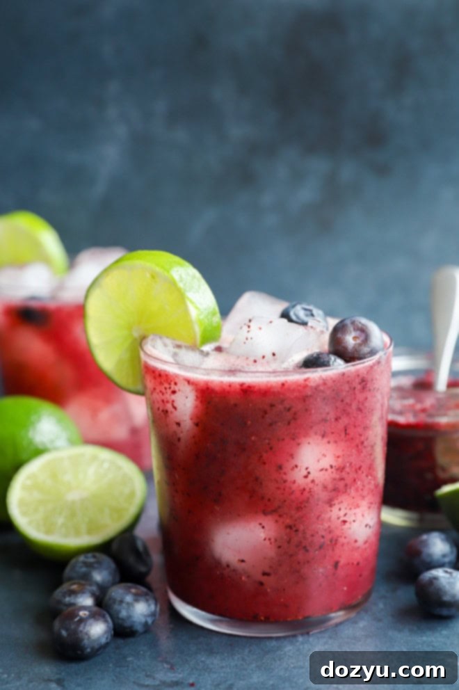 Blueberry Margarita 7 Close-up of a fresh berry cocktail with tequila and lime in a glass, garnished beautifully.