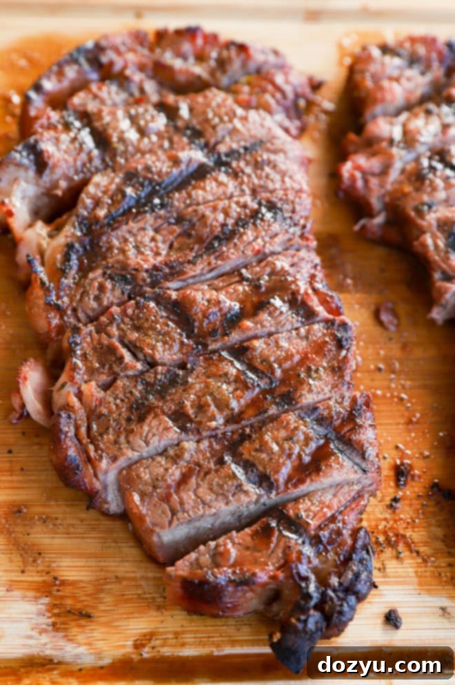 Grilled New York Strip Perfection 2 Perfectly sliced grilled New York strip steak on a cutting board, ready to be served