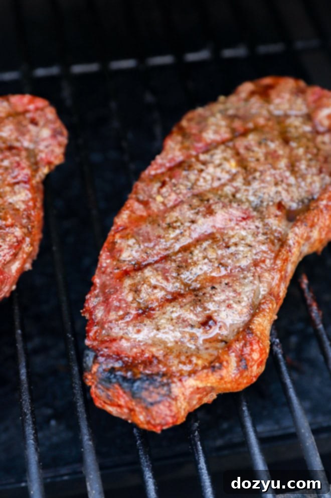 Grilled New York Strip Perfection 7 New York strip steak cooking on a hot grill with prominent grill marks