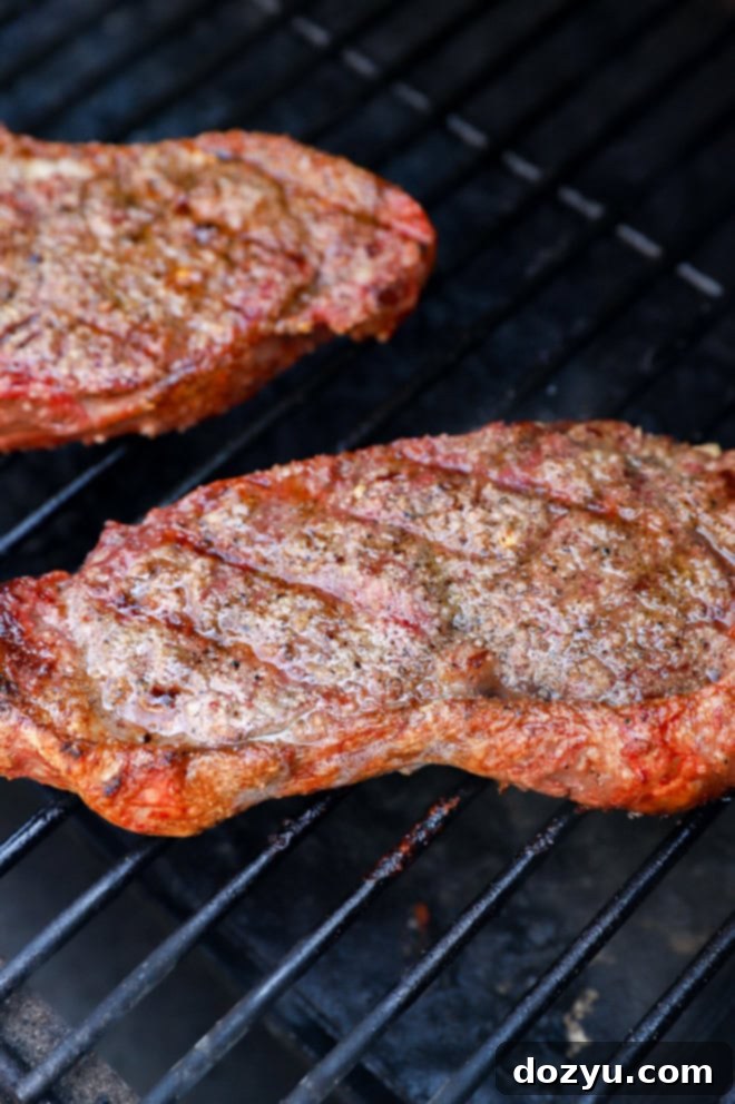 Grilled New York Strip Perfection 10 Multiple cuts of New York strip steak cooking on a grill, showing various stages of searing