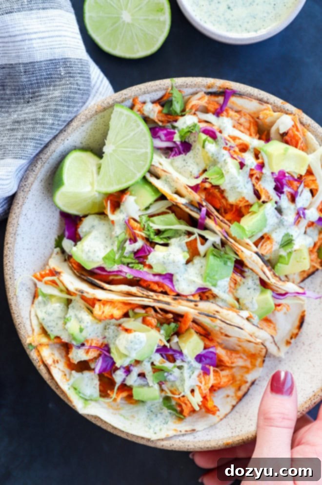 Zesty Cilantro Ranch Buffalo Chicken Tacos 6 hand holding bowl of spicy tacos with fresh limes