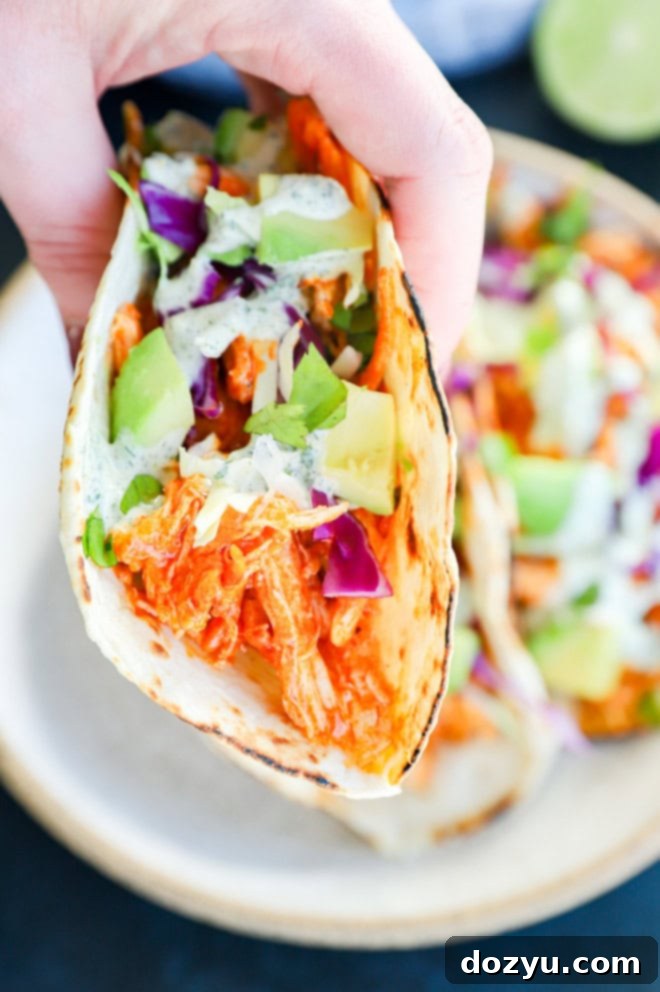 Zesty Cilantro Ranch Buffalo Chicken Tacos 7 hand holding buffalo chicken taco with ranch on top
