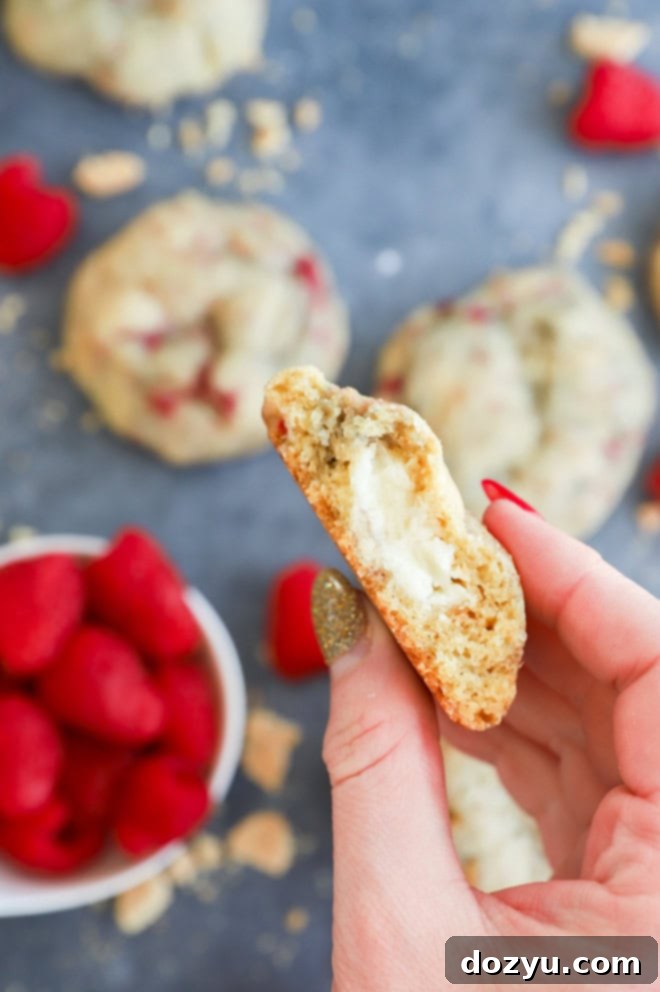 Raspberry Cheesecake Cookie Fusion 9 Hand holding half of a fruity cream cheese filled treat