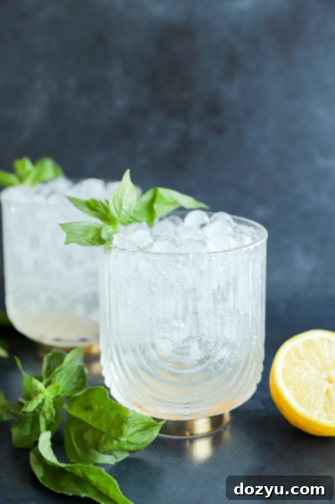 Gin Basil Smash 8 Artfully arranged fresh herbs and citrus around a gin cocktail glass, highlighting the ingredients.