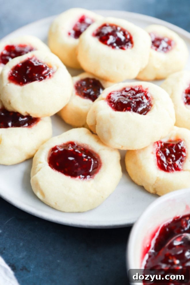 Jammy Raspberry Thumbprints 8 raspberry thumbprint cookies on plate with jam