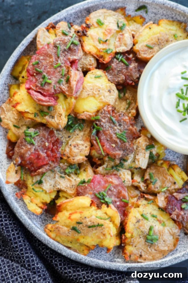 Golden Crispy Smashed Potatoes 9 smashed fingerling potatoes on platter with sour cream in a bowl