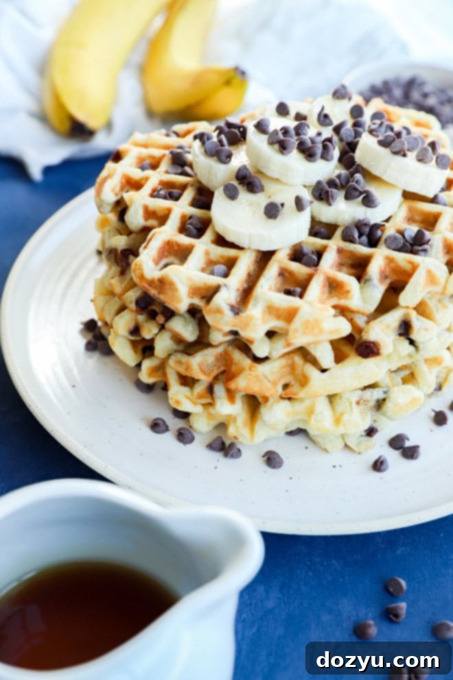 Ultimate Banana Chocolate Chip Waffles 7 Image of a stack of banana waffles with fresh banana slices and chocolate chips as toppings