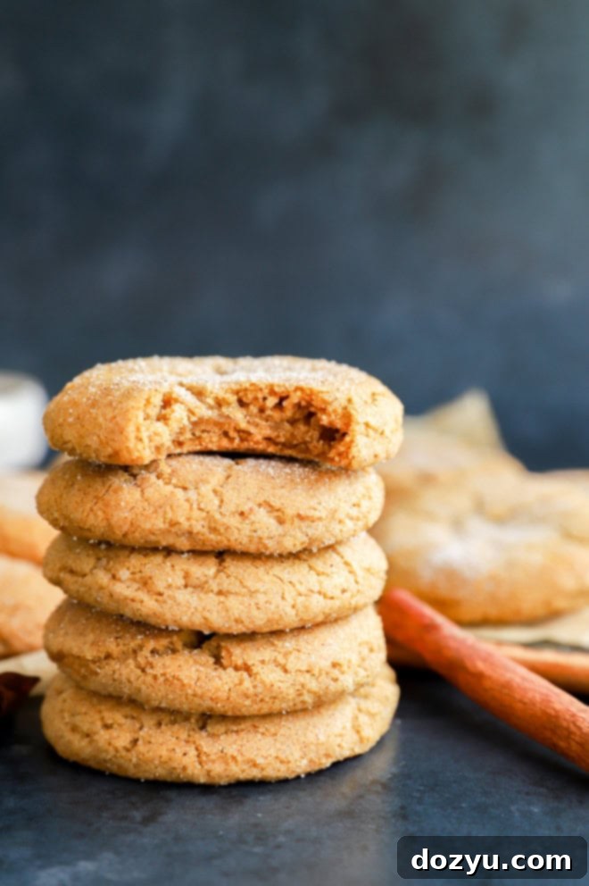 Autumn Pumpkin Spice Cookies 6 A soft, chewy pumpkin pie spice cookie with a bite taken out, showing its tender interior, stacked among others.