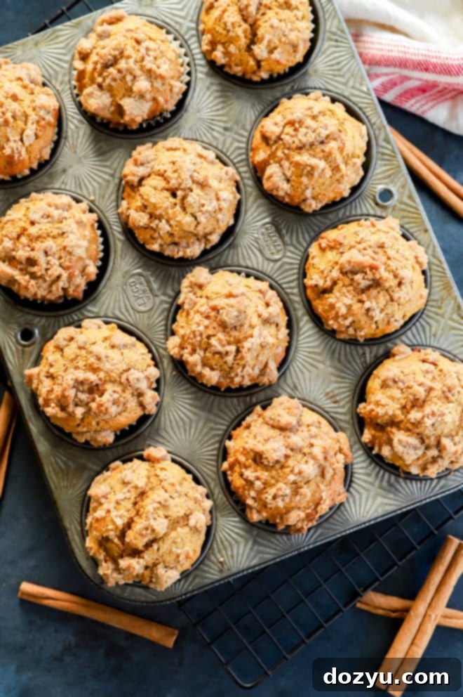 Spiced Pumpkin Banana Muffins 12 pumpkin banana muffins in muffin tin with cinnamon sticks and striped linen