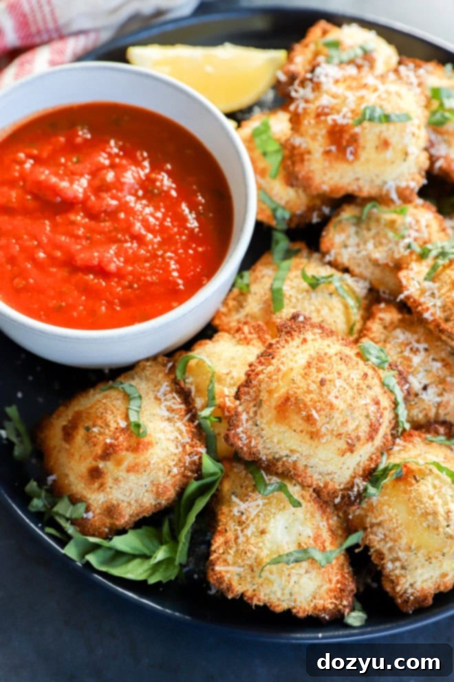Golden Air Fryer Ravioli 6 air fryer ravioli on plate with sauce in a bowl