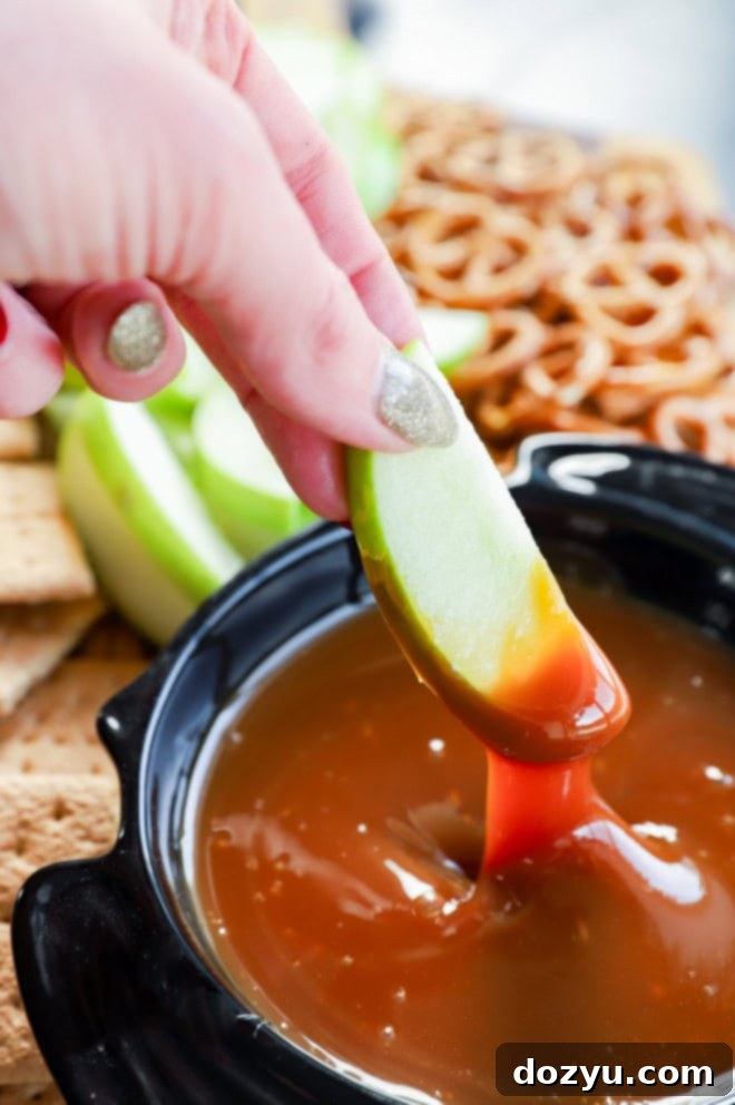Caramel Apple Delight 8 Hand dipping various fruits into a sweet caramel sauce in a bowl
