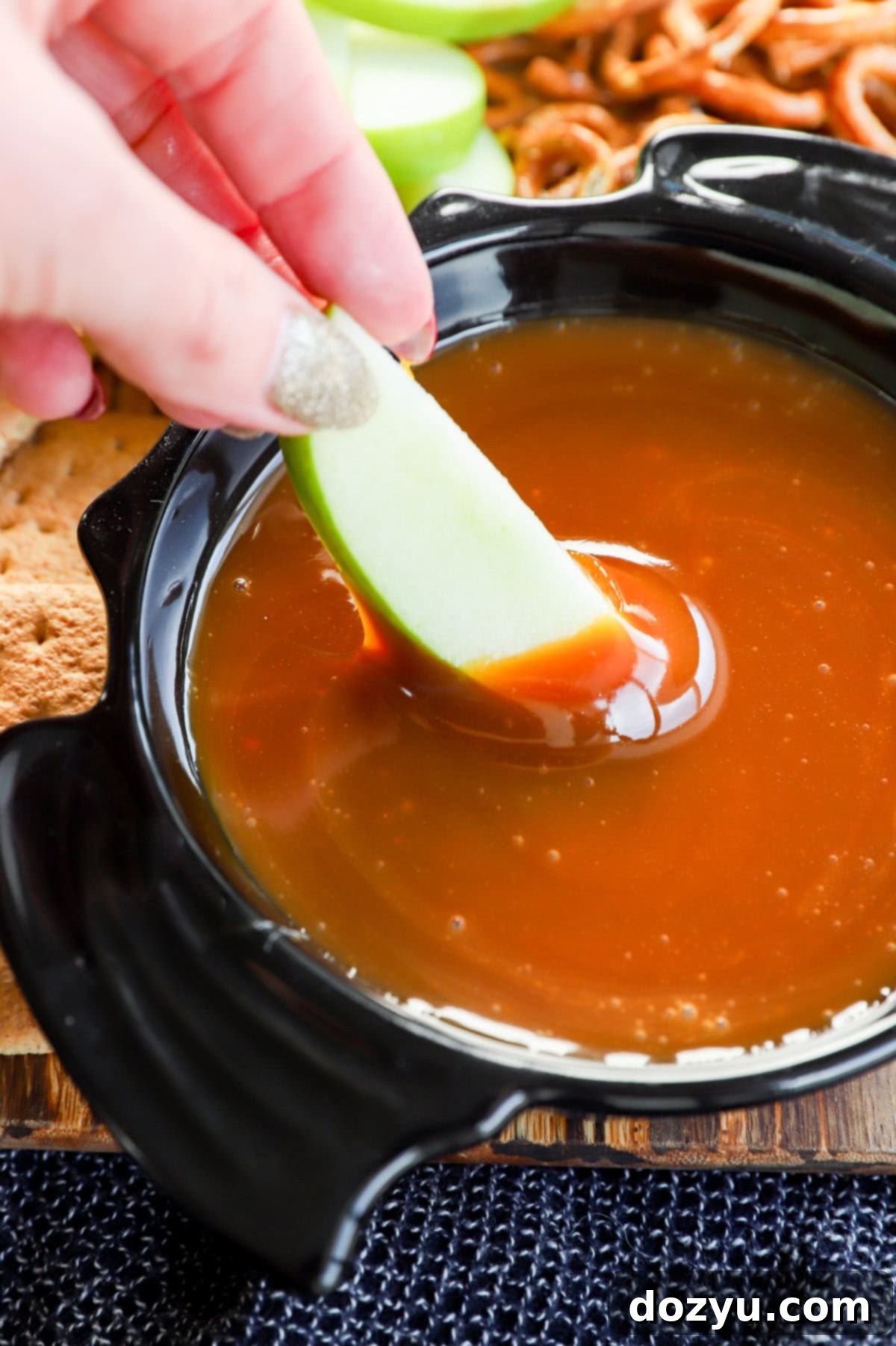Caramel Apple Delight 9 Hand dipping an apple slice in homemade caramel apple dip