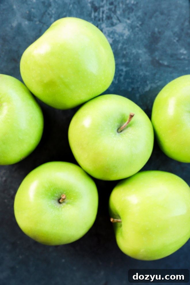 Crisp Candy Apple Treats 4 fresh green whole apples in a pile on black background