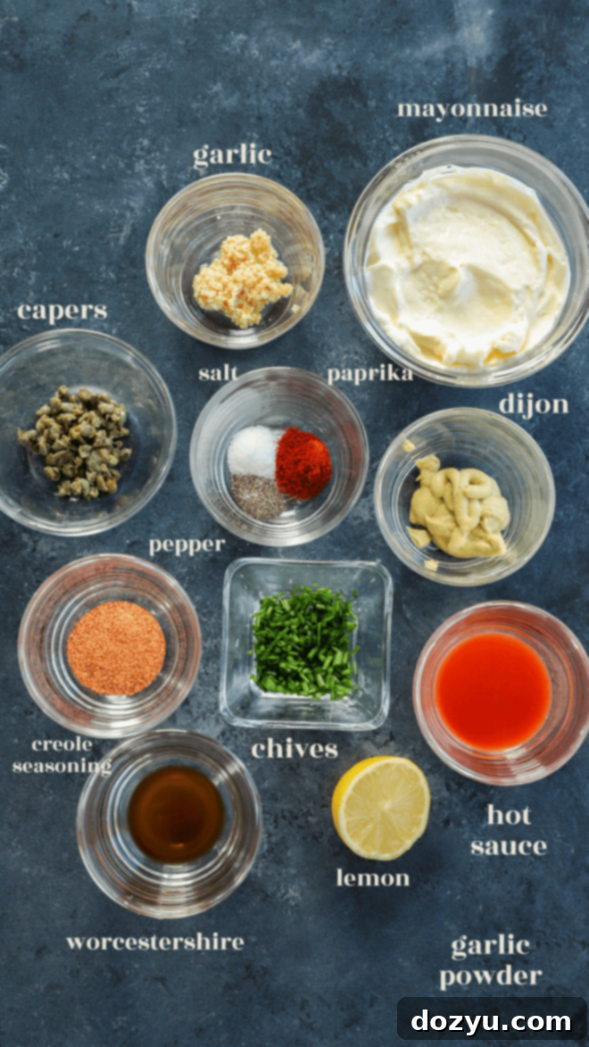 Effortless Crab Cake Sauce 3 Individual bowls of mayonnaise, Dijon mustard, lemon juice, minced garlic, Worcestershire sauce, hot sauce, Creole seasoning, smoked paprika, salt, pepper, capers, and chives, labeled as ingredients for homemade crab cake sauce.