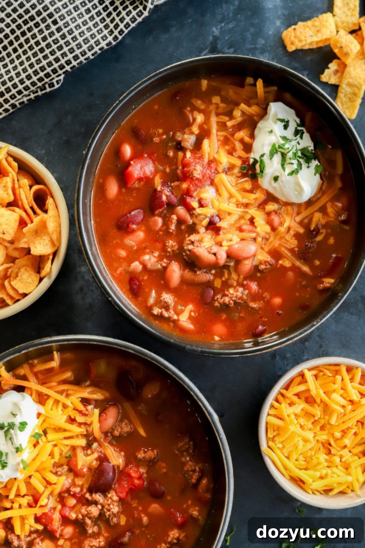 Effortless Instant Pot Chili 8 Bowls of Instant Pot Chili topped with cheese, sour cream, and parsley with Fritos on the side, highlighting the delicious result.