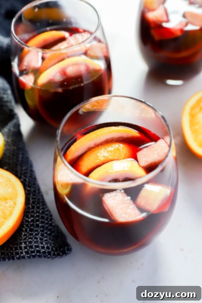 Timeless Red Sangria 2 Glasses of fruity red sangria punch with orange halves and a napkin