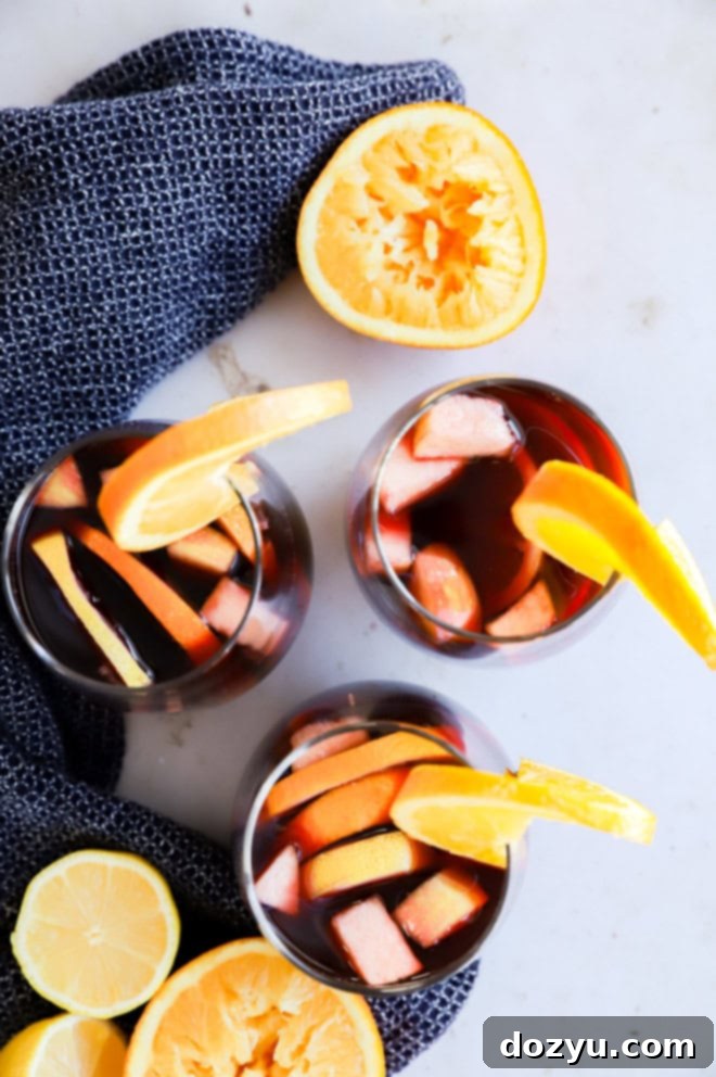 Timeless Red Sangria 6 Three glasses of red sangria with fresh fruit and orange halves on a linen cloth