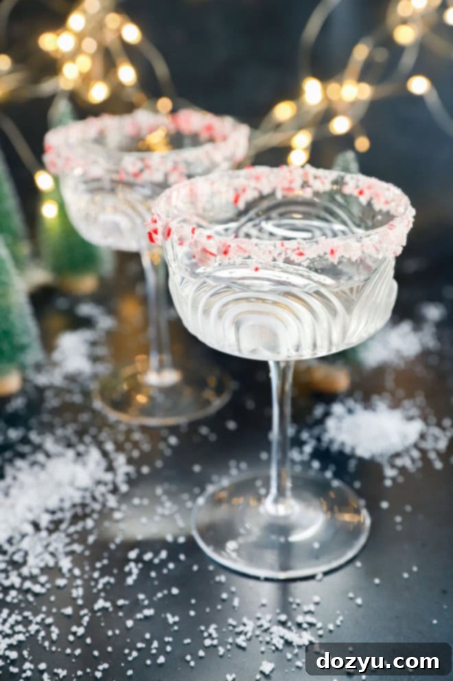 Refreshing Peppermint Martini 6 Two peppermint martinis in coupe glasses, surrounded by soft twinkle lights and a snowy background, perfect for a winter evening