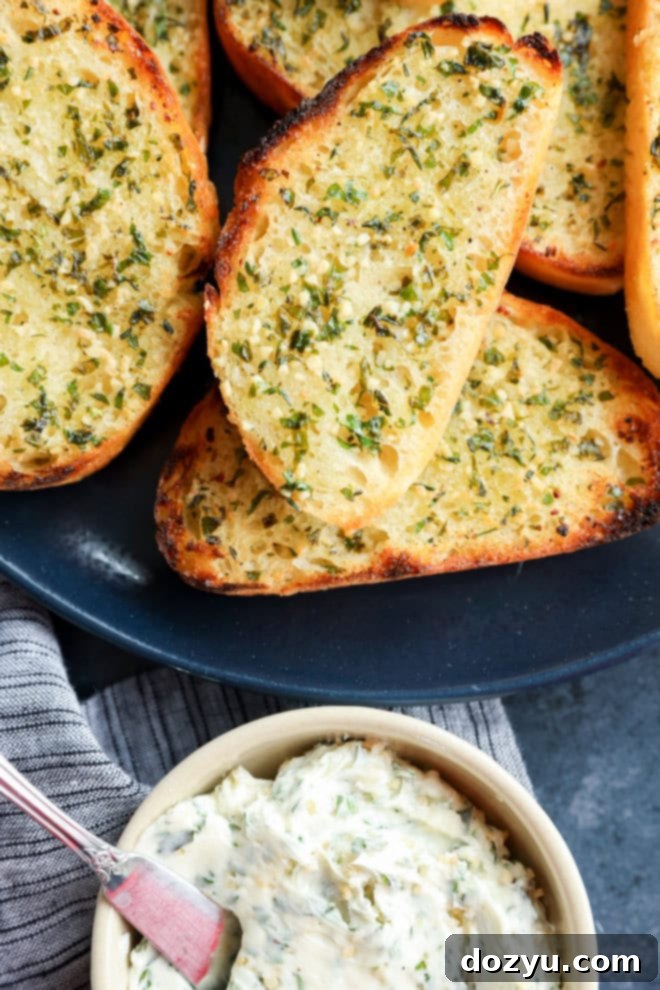 Artisan Sourdough Garlic Toast 7 Bowl of garlic herb butter next to a plate of piled-up sourdough garlic toast slices