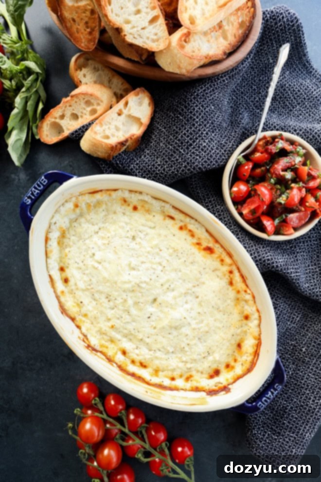 Warm Goat Cheese Dip 6 overhead image of hot cheese dip in baking dish with tomato topping in bowl and toasted bread slices