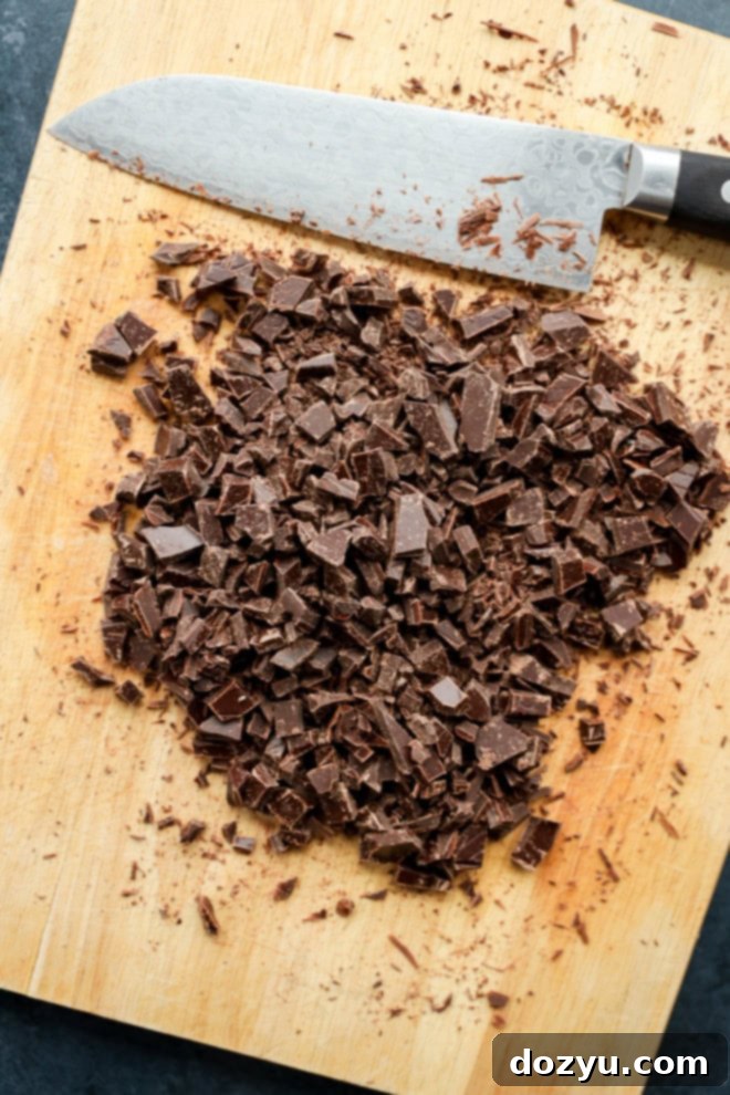 Decadent Baileys Cheesecake 7 Finely chopped dark chocolate on a wooden cutting board, ready to be used for the ganache topping.