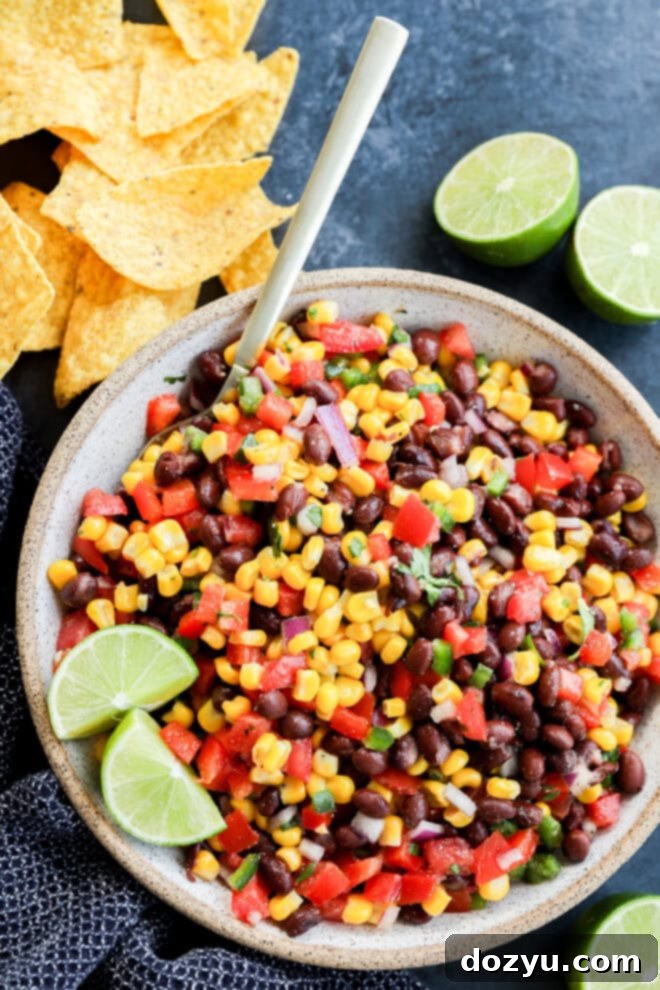 Fiesta Black Bean Corn Dip 2 fresh and easy Black bean corn salsa dip in a bowl with a spoon and tortilla chips all around