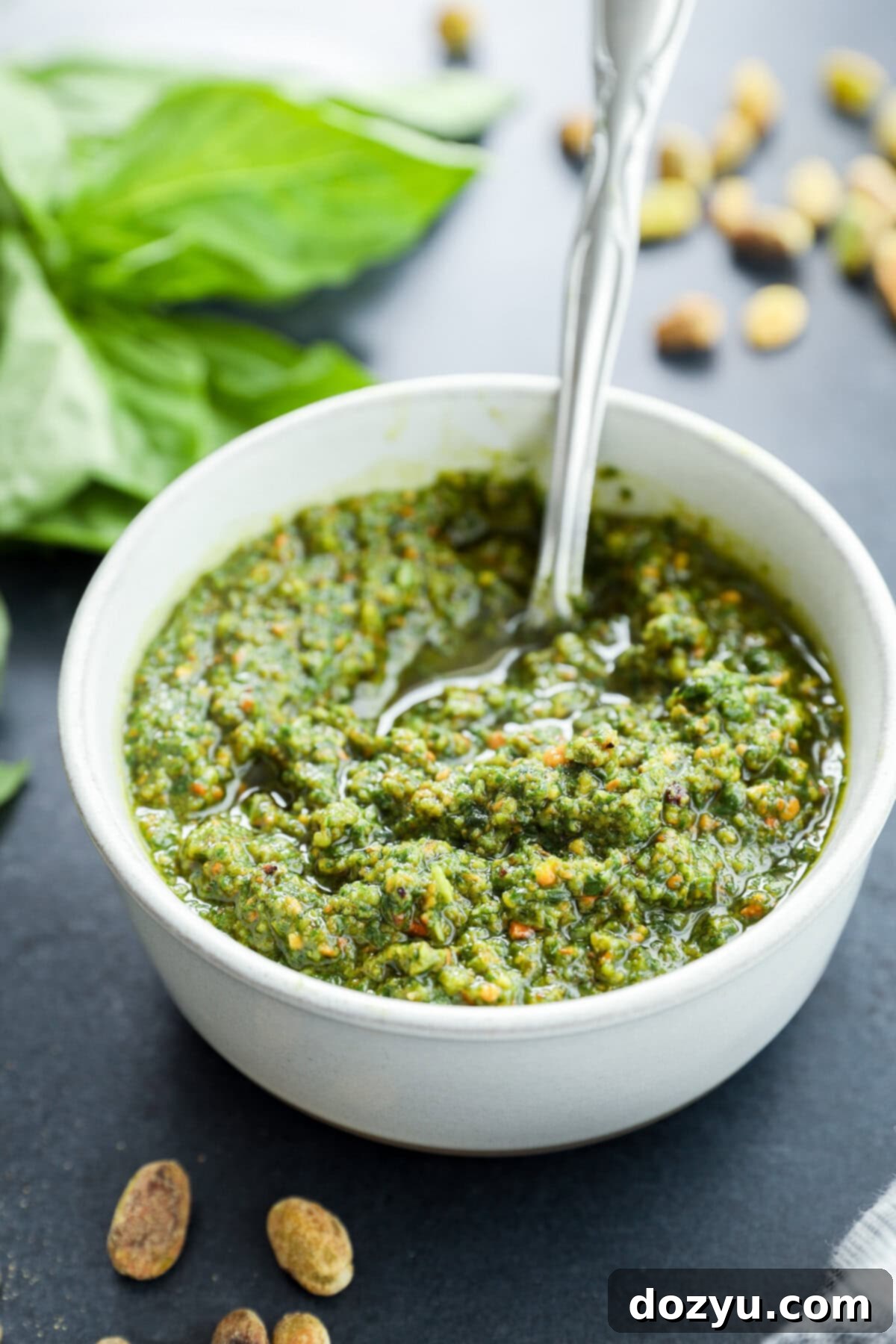 Verdant Pistachio Sauce 11 Pistachio basil pesto recipe in white pottery bowl with pistachios on the side