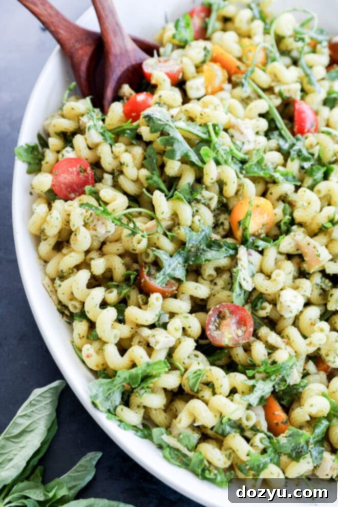 Zesty Pesto Chicken Pasta Salad 7 Easy light lunch or dinner made with poultry and cavatappi in a large white bowl with fresh basil
