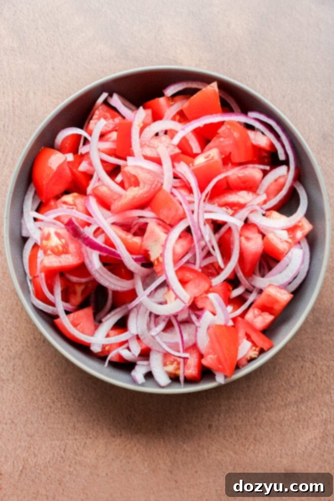Zesty Tomato Onion Salad 4 making Tomato onion salad in a bowl before pouring on dressing