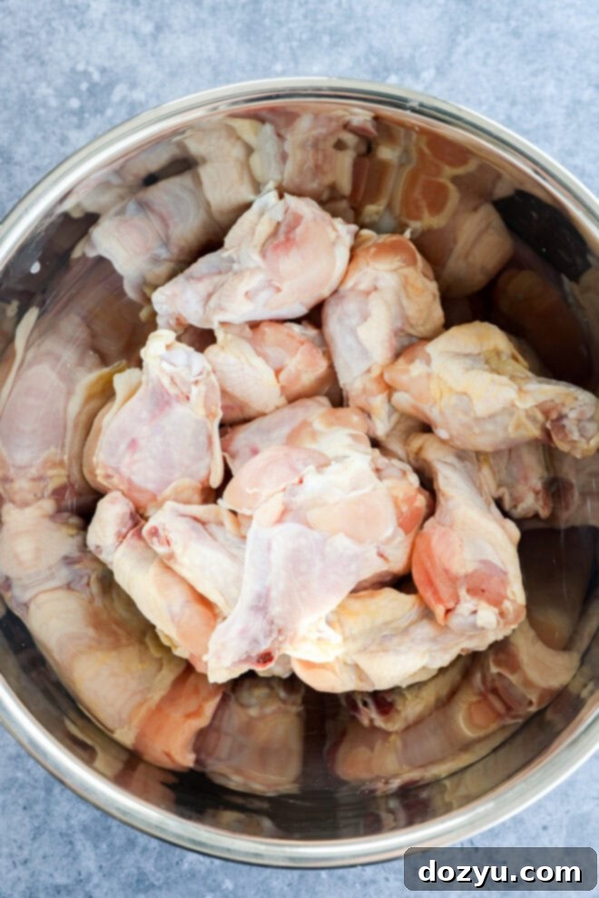 Foolproof Smoked Chicken Wings 3 Raw chicken wings in a large metal bowl, seasoned and ready for the smoker.